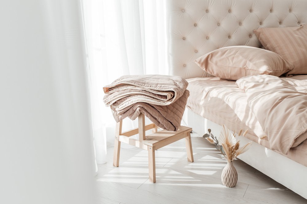 Cozy,Folded,Beige,Blanket,On,Wooden,Stool,Next,To,A
